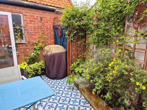 a patio with a blue table and some flowers at Shoemakers Cottage, Halesworth in Halesworth