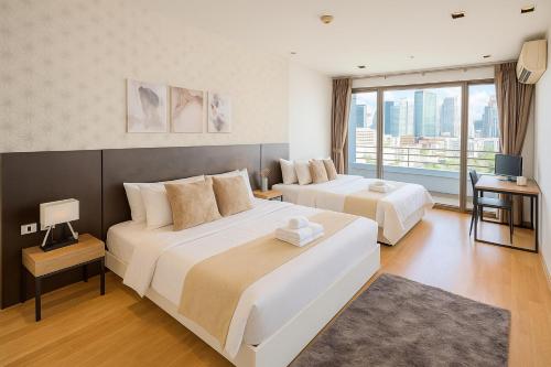 a hotel room with two beds and a window at Executive Suite 2 Beds Nana BTS 5 mins in Bangkok