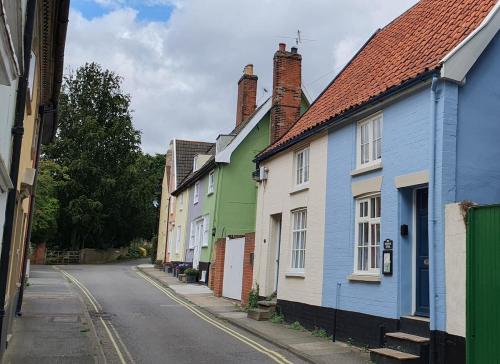 a row of colorful houses on a street at Shoemakers Cottage, Halesworth in Halesworth