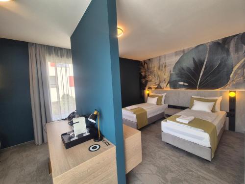 a hotel room with two beds and a desk at Energy Hotel & Business Center in Paks