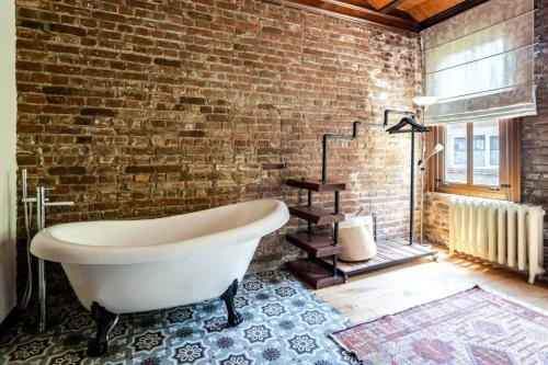 Cette chambre dispose d'une baignoire et d'un mur en briques. dans l'établissement Chic 2br Retreat House - Heart Of Cihangir! #394, à Istanbul