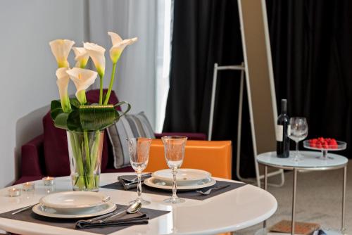 a table with plates and a vase with flowers on it at Priska Med Luxury Rooms in Split