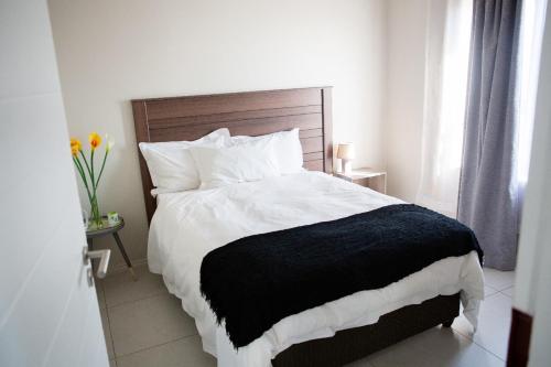 a bedroom with a bed with a black and white blanket at Oasis Comfort Apartment in Midrand