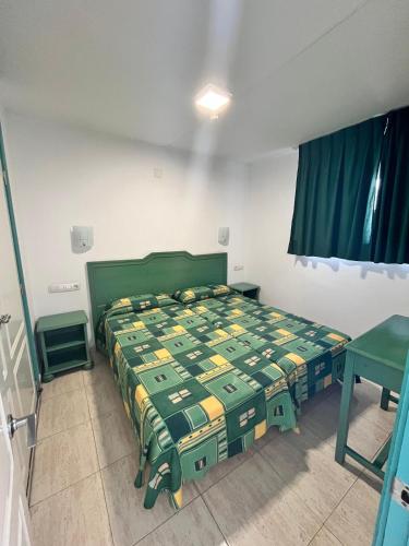a bedroom with a bed with a green bedspread at Apartamentos Florida Gran Canaria Adults Only in Puerto Rico de Gran Canaria