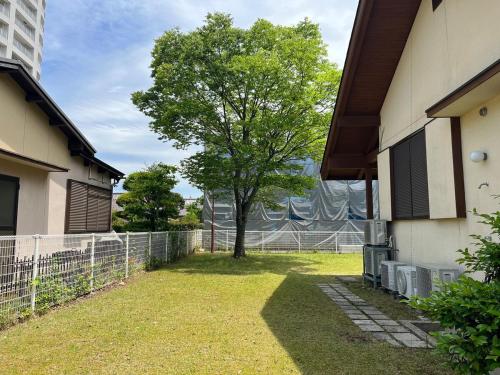 a tree in a yard next to a building at UMIIE-小松浜-Private STAY in Miyazu