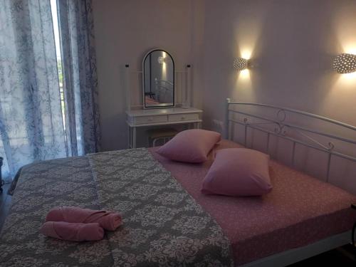 a bedroom with a bed with pink pillows and a mirror at Agnanti Apartment in Órmos