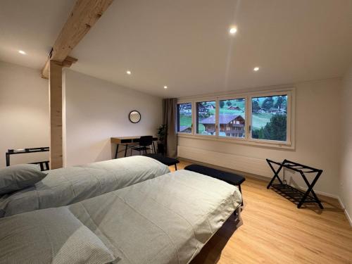 a bedroom with two beds and a large window at Des Alpes Sky Apartment in Beatenberg