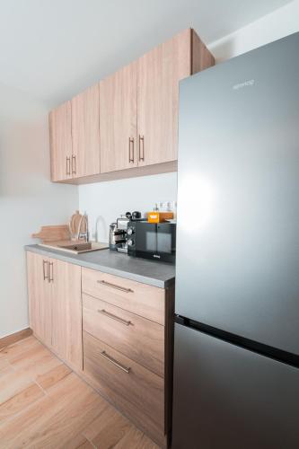 a kitchen with a stainless steel refrigerator and wooden cabinets at Harmónia Ház in Orfű