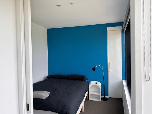 a bedroom with a blue accent wall and a bed at Top-Floor 2BR Apt, 270 deg Skyline, Free Parking in Melbourne