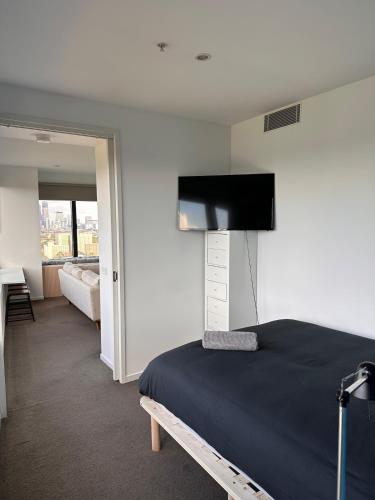 a bedroom with a bed and a flat screen tv at Top-Floor 2BR Apt, 270 deg Skyline, Free Parking in Melbourne