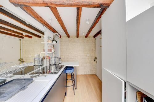 - une cuisine avec des comptoirs blancs et des plafonds en bois dans l'établissement Le Renaud - Le Marais - Wifi - Balcon, à Paris