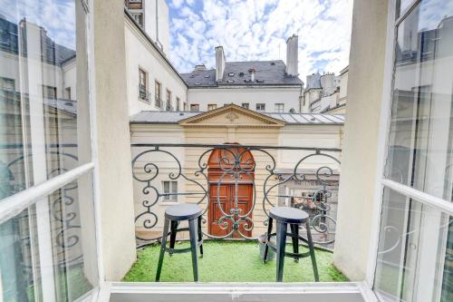 d'un balcon avec deux tabourets et une porte rouge. dans l'établissement Le Renaud - Le Marais - Wifi - Balcon, à Paris