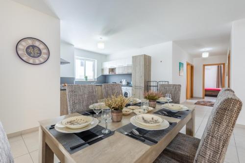 a dining room with a table with chairs and a clock at Modern 3BR w Terrace Near Beaches & Restaurants by QuickTrips in St. Paul's Bay