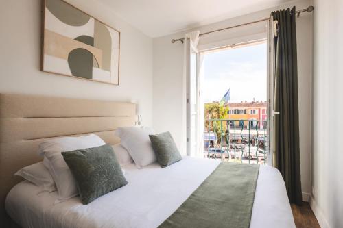 a bedroom with a bed and a large window at Le Suffren Hôtel in Grimaud