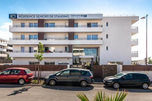 three cars parked in a parking lot in front of a building at Zenitude Hôtel-Résidences Perpignan in Perpignan