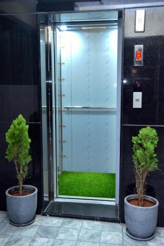 two potted trees sitting in front of an elevator at Tech Park Residency Manyata in Bengaluru
