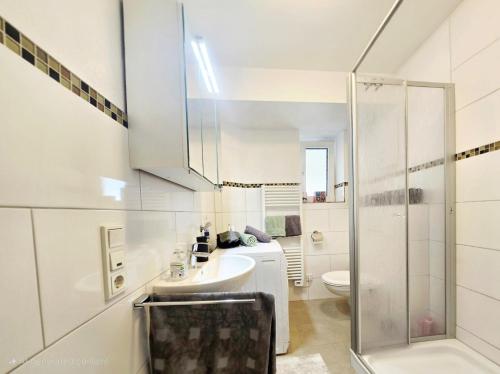 une salle de bain blanche avec un lavabo et une douche dans l'établissement 5 Minuten zur historischen Altstadt gemütliche Ferienwohnung in Trier Heilig-Kreuz, à Trèves