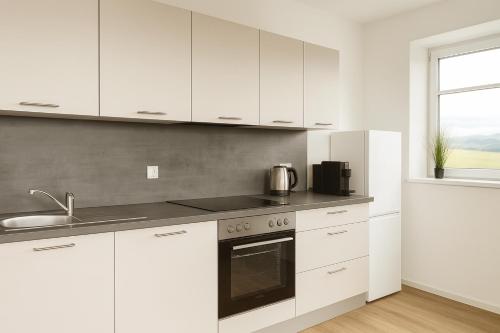 a white kitchen with white cabinets and a sink at SMS-Homes I Auszeit am See #1 in Waltenhofen