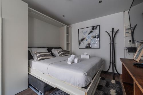 une chambre avec un lit avec des draps blancs et des oreillers dans l'établissement Studio Or - Studio à la Krutenau, à Strasbourg