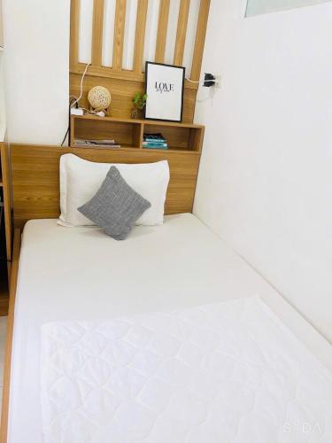 a white bed with a wooden headboard and two pillows at Hello SaiGon Homestay in Ho Chi Minh City