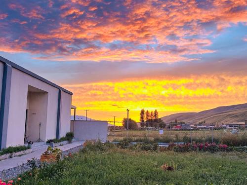 a sunset over a field with a building and flowers at Nalati Jianxian B&B in Narat