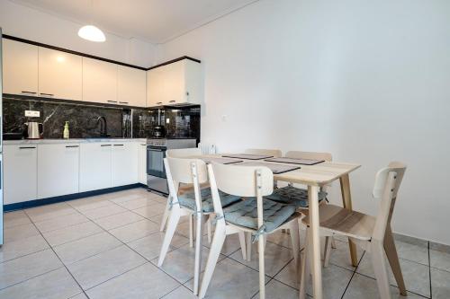 a kitchen with white cabinets and a wooden table and chairs at Barbara's sweet home Glyfada by ΜΡS in Athens