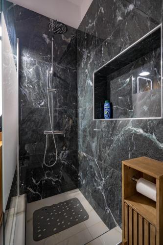 a bathroom with a shower with black marble at Barbara's sweet home Glyfada by ΜΡS in Athens