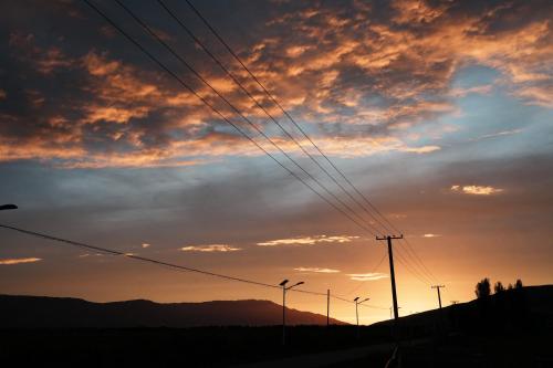 a sunset with power poles and wires in a field at Nalati Jianxian B&B in Narat