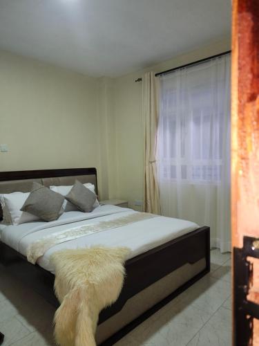 a bedroom with a large bed with a furry rug on it at kingdom corner suites in Nairobi