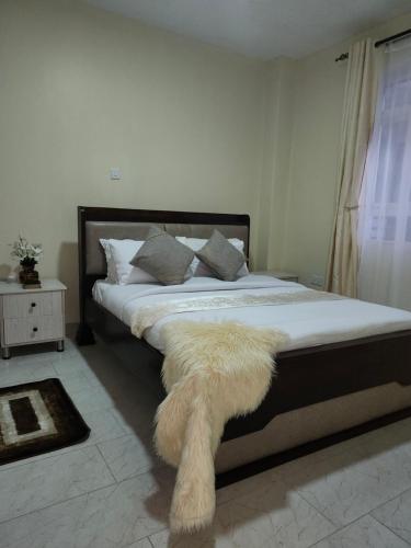 a bedroom with a bed with a furry rug on it at kingdom corner suites in Nairobi