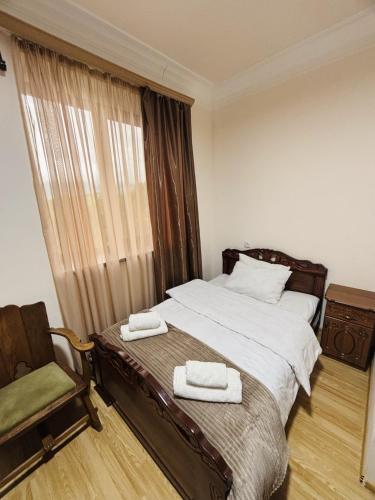 a bedroom with a bed and a chair and a window at j&s family hotel in Vanadzor