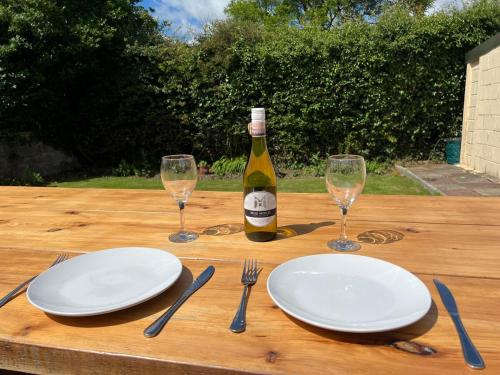 a table with two plates and a bottle of wine at 2 bedroom Lake district cottage in Cockermouth