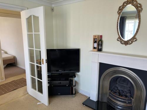 a living room with a television and a fireplace at 2 bedroom Lake district cottage in Cockermouth