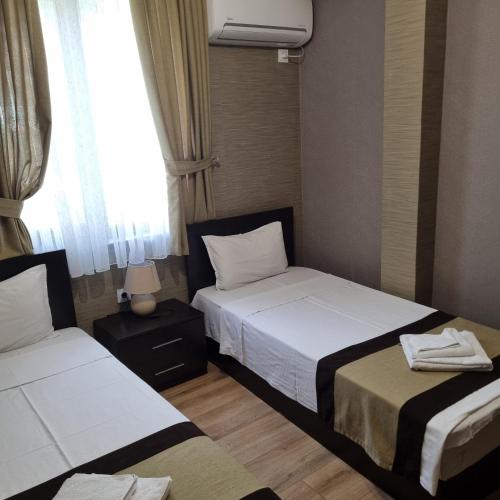 two beds in a small room with a window at Къща за гости Тони in Zlatograd