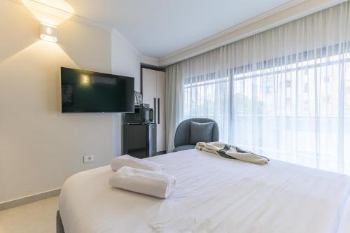 a bedroom with a white bed with a tv on the wall at CityZen - Boutique Studios in Achrafieh in Beirut