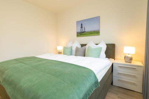 a bedroom with a large bed with a green blanket at Dorumer Sielhuus 4 - Ferienwohnung mit Garten und Sauna in Dorum