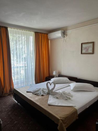 ein Schlafzimmer mit zwei Betten mit weißer Bettwäsche und einem Fenster in der Unterkunft Hotel National in Mamaia