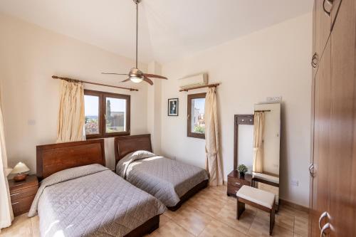 a bedroom with two beds and a ceiling fan at Villa Tsikkos Tria in Polis Chrysochous