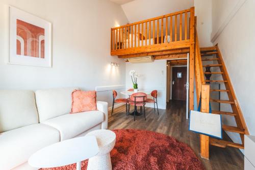 a living room with a white couch and a spiral staircase at Le Suffren Hôtel in Grimaud