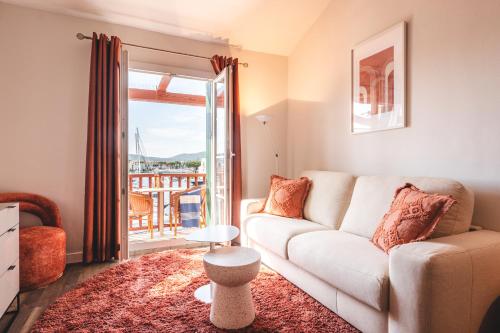 a living room with a couch and a balcony at Le Suffren Hôtel in Grimaud