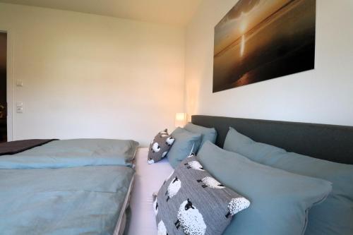 a bedroom with a bed and pillows and a painting at Dorumer Sielhuus 10 - Sauna und balkon, strandnah in Dorum
