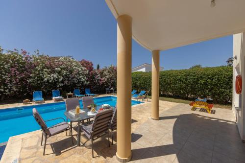 a patio with a table and chairs next to a pool at Villa Tsikkos Tria in Polis Chrysochous