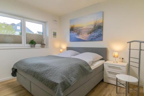 a bedroom with a bed and a table and two windows at Herz von Kellenhusen 2 mit Garten und Sauna in Kellenhusen