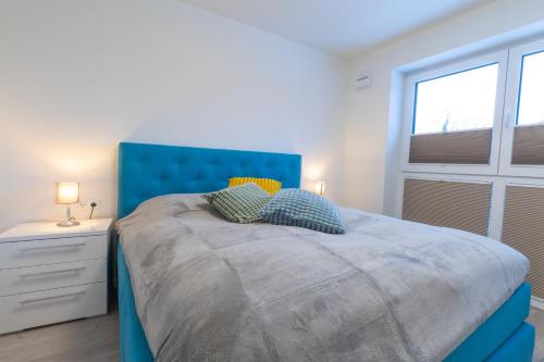 ein Schlafzimmer mit einem blauen Bett und einem Fenster in der Unterkunft Wolke 7 mit Sauna und Balkon - Hunde willkommen in Kellenhusen
