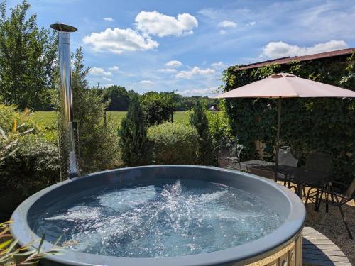 a hot tub in a garden with an umbrella at Škorničkův statek in Chlum u Třeboně