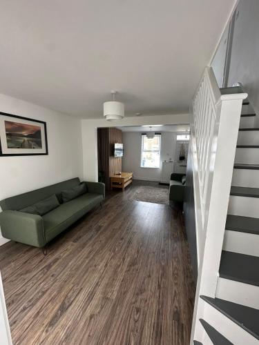 a living room with a green couch and a staircase at Heart of Oxford in Oxford