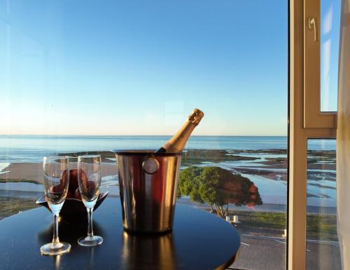 une bouteille de champagne dans un seau sur une table avec deux verres dans l'établissement Hotel y Casino Del Río - Las Grutas, à Las Grutas