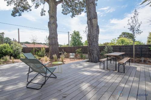une terrasse avec une table, un banc et deux arbres dans l'établissement Sekoya Sundeck - Proche plage - golf, à Pornic