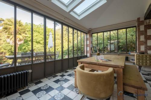 une véranda avec une table, des chaises et des fenêtres dans l'établissement L'Oasis - Proche plage - Wifi - Jardin, à Pornic