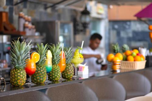 a counter with pineapple drinks and a man in the background at Two Seasons Hotel & Apartments in Dubai